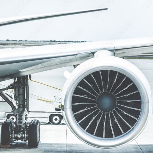 Zoom on airplane wing and reactor in an airport